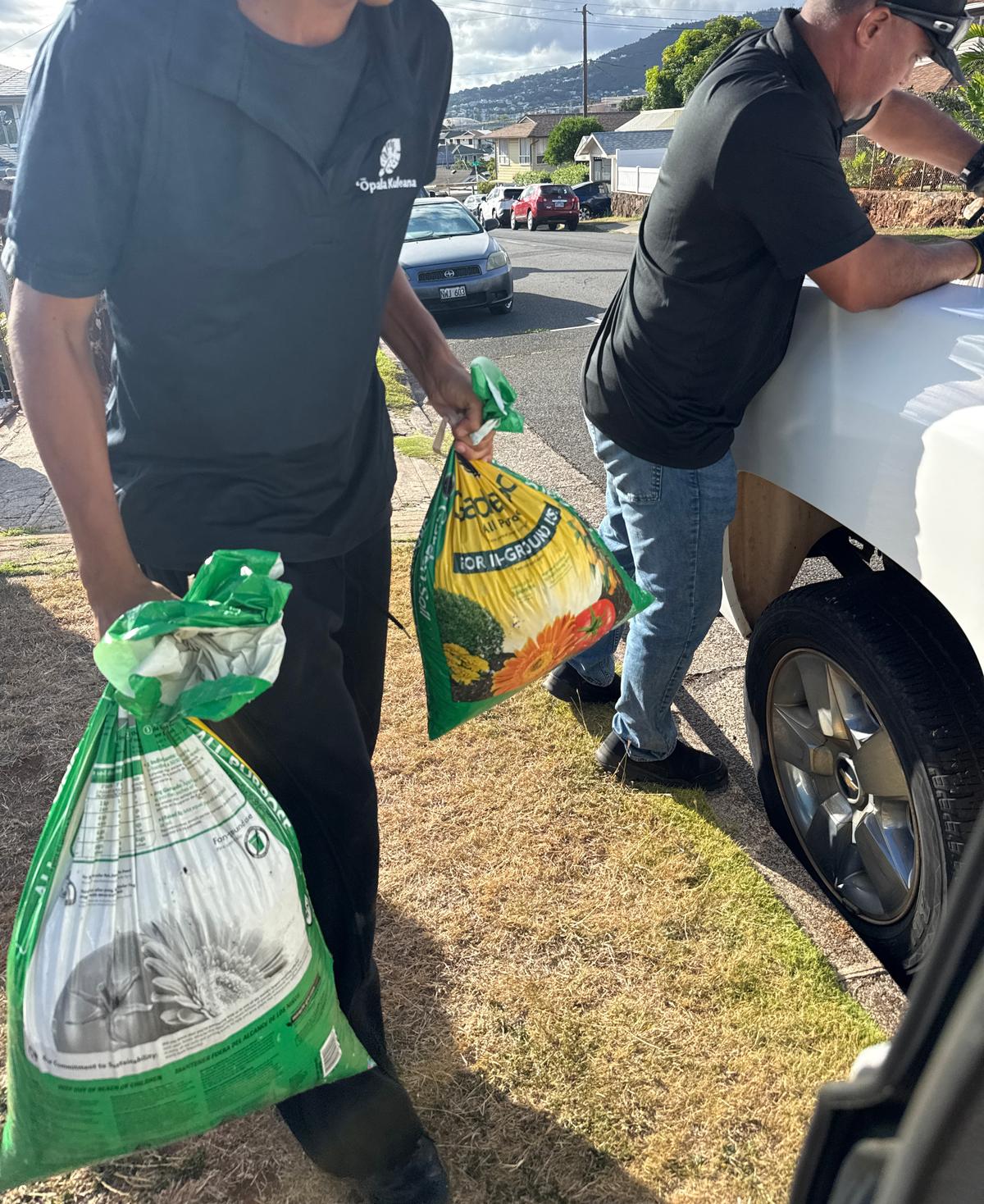 ʻŌpala Kuleana crew carrying junk removal bags in Oahu neighborhood